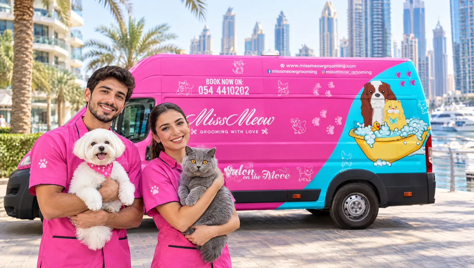 Two Miss Meow groomers holding a groomed Maltese dog and a British Shorthair cat in front of the pink mobile grooming van in Dubai Marina